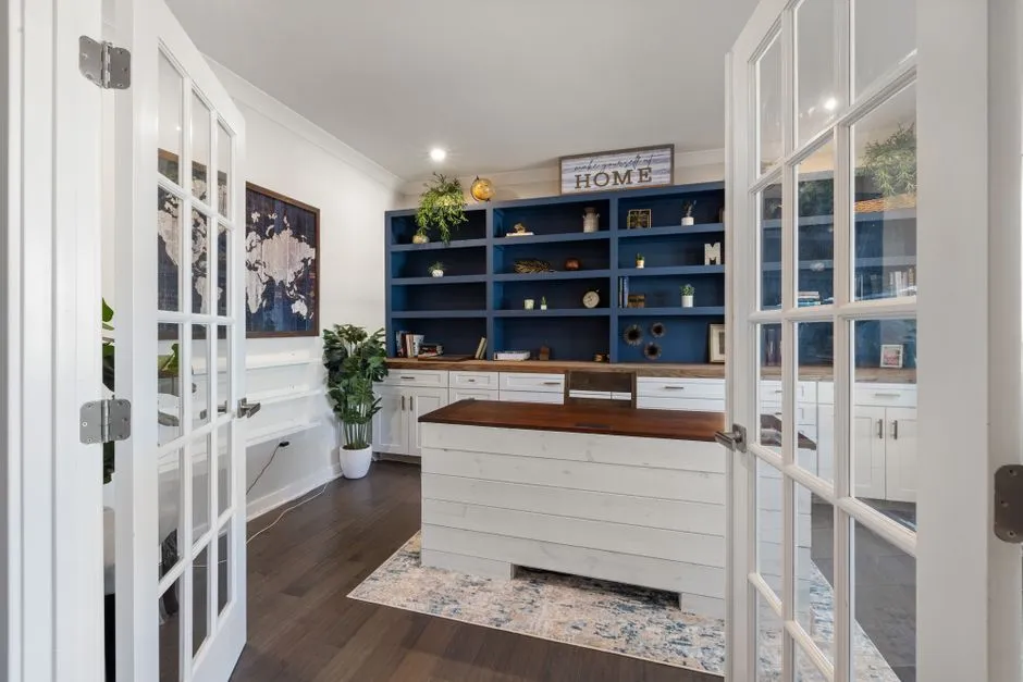 A bright, tidy home office corner with a desk and shelving, illustrating the kind of dedicated workspace a closable door protects.