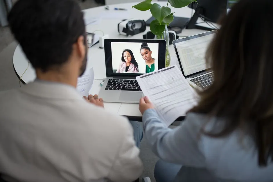 Two professionals conducting a virtual job interview over laptops, illustrating a remote hiring conversation.
